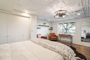 A bedroom with a large bed, a chest of drawers, a chair, and a ceiling with a decorative light fixture. - The Lodge at Shaw Ranch | Hocking Hills, 30 Acres (Rockbridge)