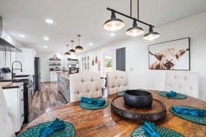 A modern kitchen with white cabinets, a dining area with a wooden table, and a large framed animal picture on the wall. - The Lodge at Shaw Ranch | Hocking Hills, 30 Acres (Rockbridge)