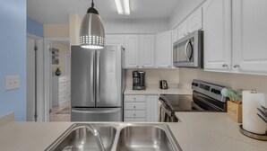 A modern kitchen with stainless steel appliances, white cabinets, and a double sink. -  Welcome to Your Beachside Escape in Destin! (Miramar Beach)