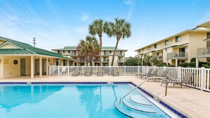 A swimming pool with lounge chairs and a white fence, surrounded by multi-story buildings with balconies. -  Welcome to Your Beachside Escape in Destin! (Miramar Beach)