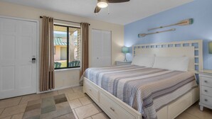 A bedroom with a bed, a nightstand, a ceiling fan, and a window with curtains. -  Welcome to Your Beachside Escape in Destin! (Miramar Beach)