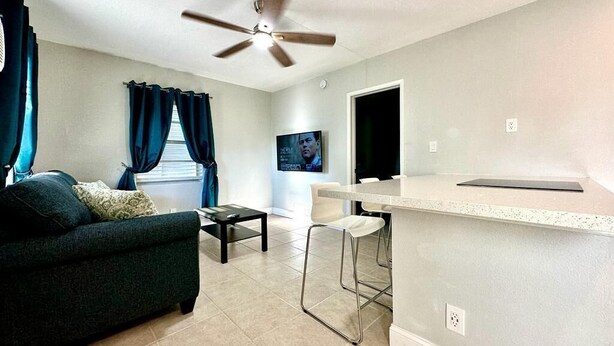 A modern living room with a sofa, a coffee table, and a bar area with stools. - 1-bedroom in Fort Lauderdale w/FREE Parking,Kitchen,Patio-8mins from FLL Airport (Fort Lauderdale)