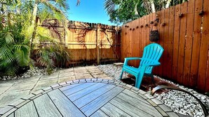 A patio area with a wooden deck, a blue plastic chair, and a wooden fence. - 1-bedroom in Fort Lauderdale w/FREE Parking,Kitchen,Patio-8mins from FLL Airport (Fort Lauderdale)