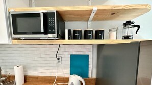 A kitchen with a microwave, coffee maker, and storage jars on a shelf. - 1-bedroom in Fort Lauderdale w/FREE Parking,Kitchen,Patio-8mins from FLL Airport (Fort Lauderdale)