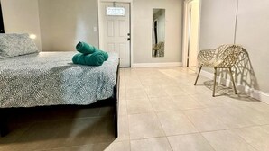 A bedroom with a bed, a ceiling fan, a door, and a chair. - 1-bedroom in Fort Lauderdale w/FREE Parking,Kitchen,Patio-8mins from FLL Airport (Fort Lauderdale)