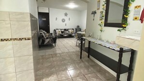 Une pièce avec un sol carrelé, un canapé, une table à manger et un miroir décoré de motifs de tournesols.