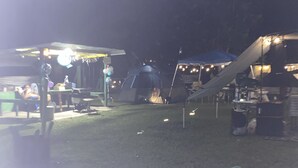 Un terrain de camping avec des tentes et un espace abrité équipé de tables et de chaises.