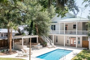 Une maison à deux étages avec une piscine, un espace salon extérieur et un patio couvert.