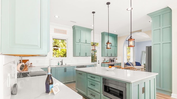 A spacious kitchen with light green cabinets, a large island, and pendant lighting. - Pura Vida Villa: Luxury Coastal Retreat With Private Heated Pool (Murrells Inlet)