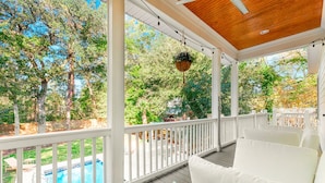 A covered outdoor area with a pool, white railings, and a hanging planter. - Pura Vida Villa: Luxury Coastal Retreat With Private Heated Pool (Murrells Inlet)