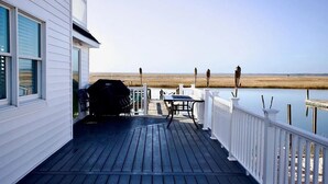 A wooden deck with a grill and table, overlooking a marshy landscape and water. - Stone Harbor Bar on the Bay (Middle Township)