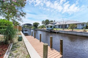 Une promenade le long du canal, avec une terrasse en bois, une maison dotée d’un porche abrité et un petit quai s’avançant dans l’eau.