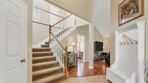A spacious living area with a wooden staircase, a fireplace, and a dining area. - Long-Term Discount!Unique 3BR canal home, Private Dock, Boat Lift, Deck! (Punta Gorda)