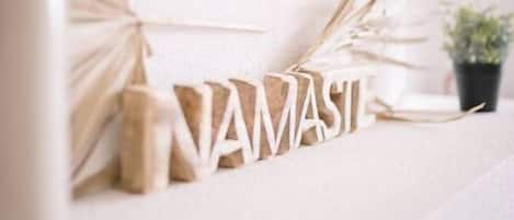 A decorative wall with the word "NAMASTE" spelled out in wooden letters, accompanied by dried plant leaves.