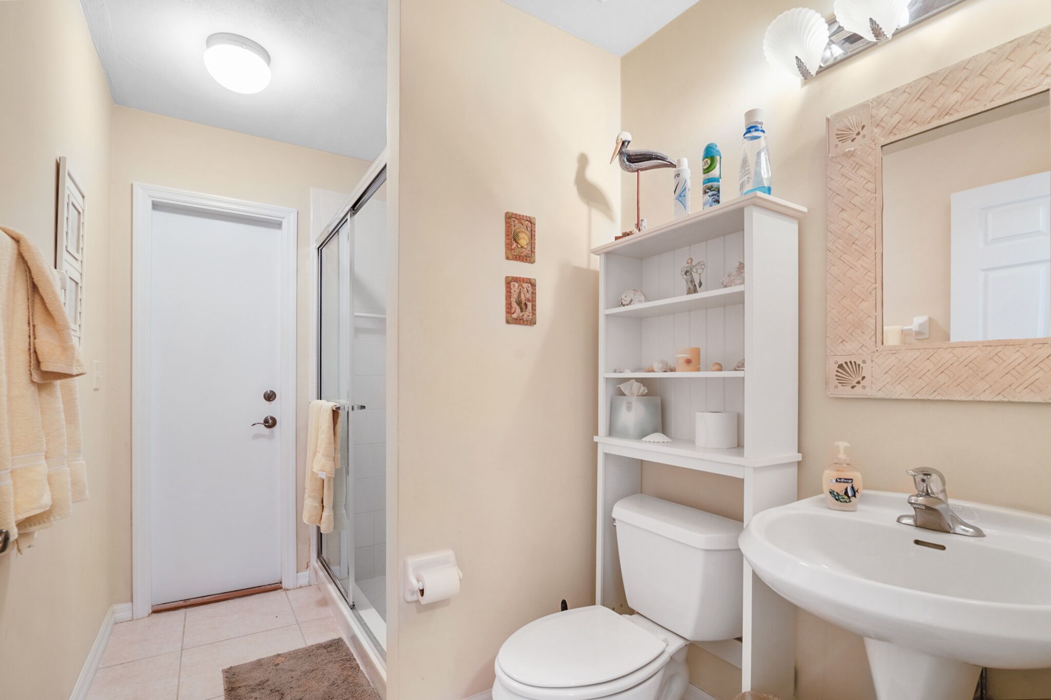 A bathroom with a toilet, sink, and glass shower enclosure.