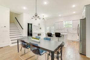 A modern kitchen with white cabinets, a stainless steel refrigerator, and a dining area with a glass table and chairs. - Modern Decatur Home ~ 7 Mi to Atlanta! (Decatur)