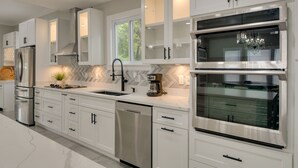 A modern kitchen with white cabinetry, stainless steel appliances, and a built-in oven. - 5 Mi to Inner Harbor: Expansive Family Getaway (Baltimore)