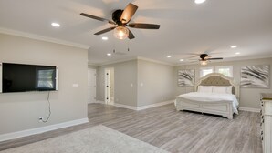 A spacious bedroom with a large bed, two ceiling fans, a TV mounted on the wall, and a walk-in closet. - 5 Mi to Inner Harbor: Expansive Family Getaway (Baltimore)