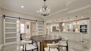 A modern kitchen with white cabinets, a central island, and a chandelier. - 5 Mi to Inner Harbor: Expansive Family Getaway (Baltimore)