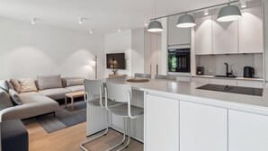 A modern kitchen with white cabinets, a central island, and pendant lighting. - 4 bedroom stunning apartment in Tossens (Tossens)