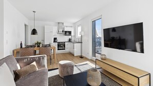 Un apartamento moderno con sala de estar, comedor, cocina y un televisor grande.