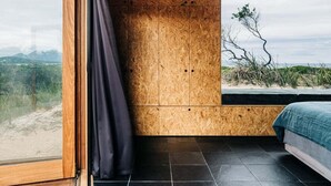 Een kamer met een groot raam, een houten kast en een bed.
