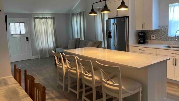 Une cuisine moderne dotée d’un îlot central, de tabourets de bar et d’un réfrigérateur.