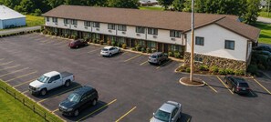 Un motel doté d’un parking, de plusieurs véhicules et d’un bâtiment dont le toit est de couleur marron.