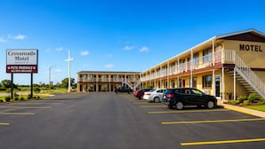 A motel with a parking lot, a sign indicating pet friendliness, and a staircase leading to the entrance. - Crossroads Motel Seiling Us 60 (Seiling)