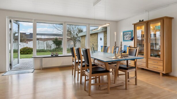 A dining area with a large table, six chairs, and a cabinet with glass doors.