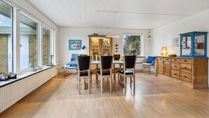 A modern kitchen with a dining area, featuring a wooden table, chairs, and a cabinet with glass doors.