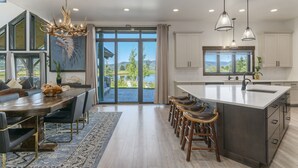 Une cuisine moderne dotée d’un grand îlot central, de tabourets de bar et offrant une vue sur l’extérieur.