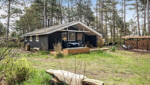 Een chalet met terras, omringd door hoge bomen.