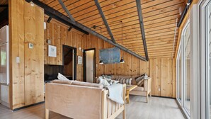 A cozy cabin interior with a wooden ceiling, a sofa, a table, and a large window. - Amazing home in Toftlund with WiFi (Toftlund)