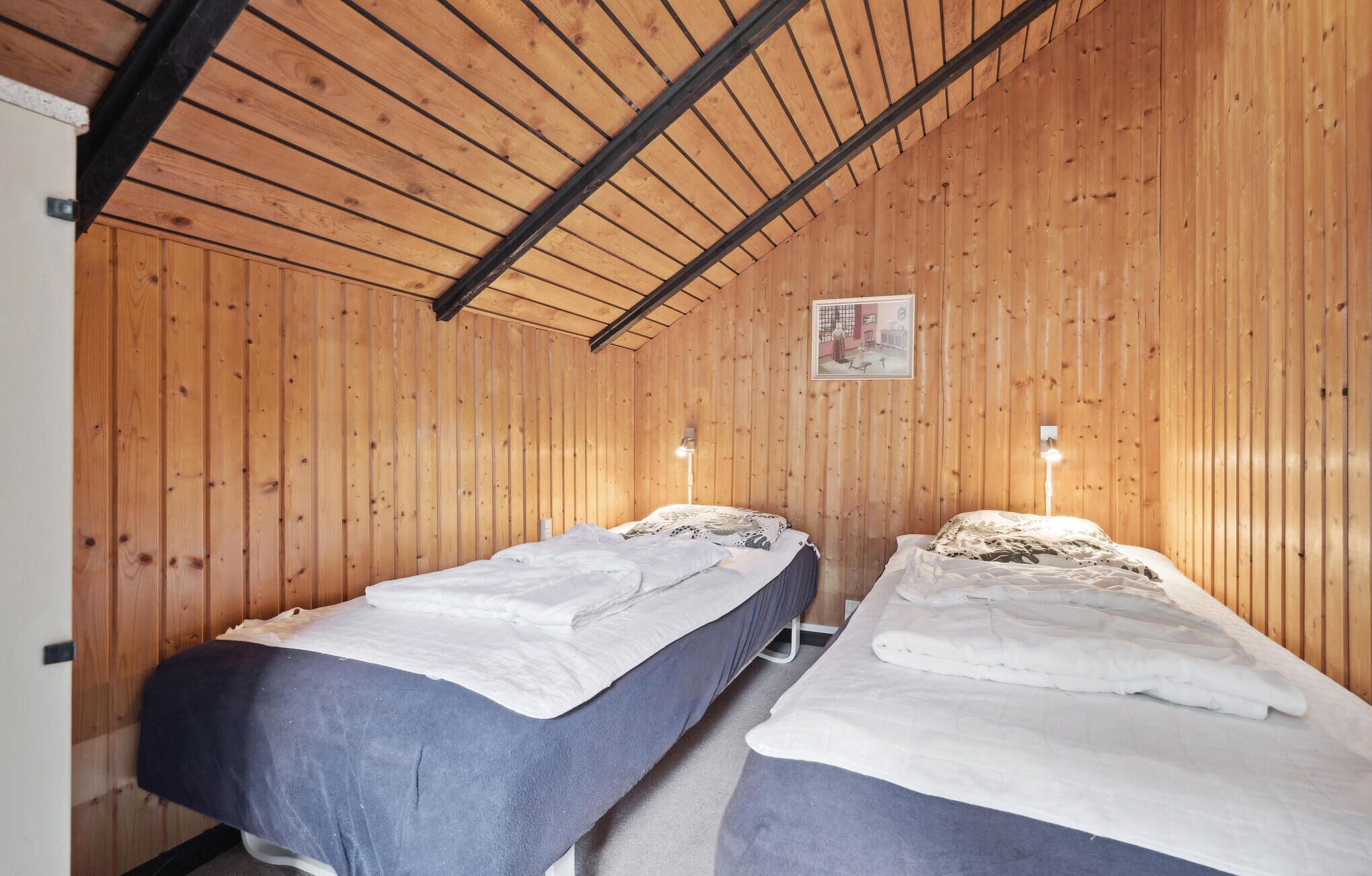Una habitación con dos camas, paredes de madera y techo inclinado.