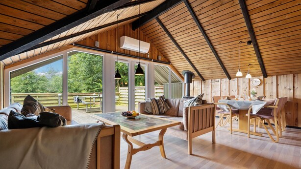 A spacious room with a high ceiling, wooden beams, a large dining table, and a cozy seating area with a sofa and chairs. - Amazing home in Toftlund with WiFi (Toftlund)