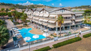 A multi-story hotel with a swimming pool, outdoor seating, and a view of the surrounding landscape. - Lovely apartment in Roseto degli Abruzzi (Roseto degli Abruzzi)