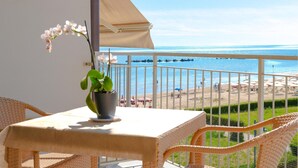 A balcony with a table and chairs, overlooking a beach with umbrellas and lounge chairs. - Lovely apartment in Roseto degli Abruzzi (Roseto degli Abruzzi)