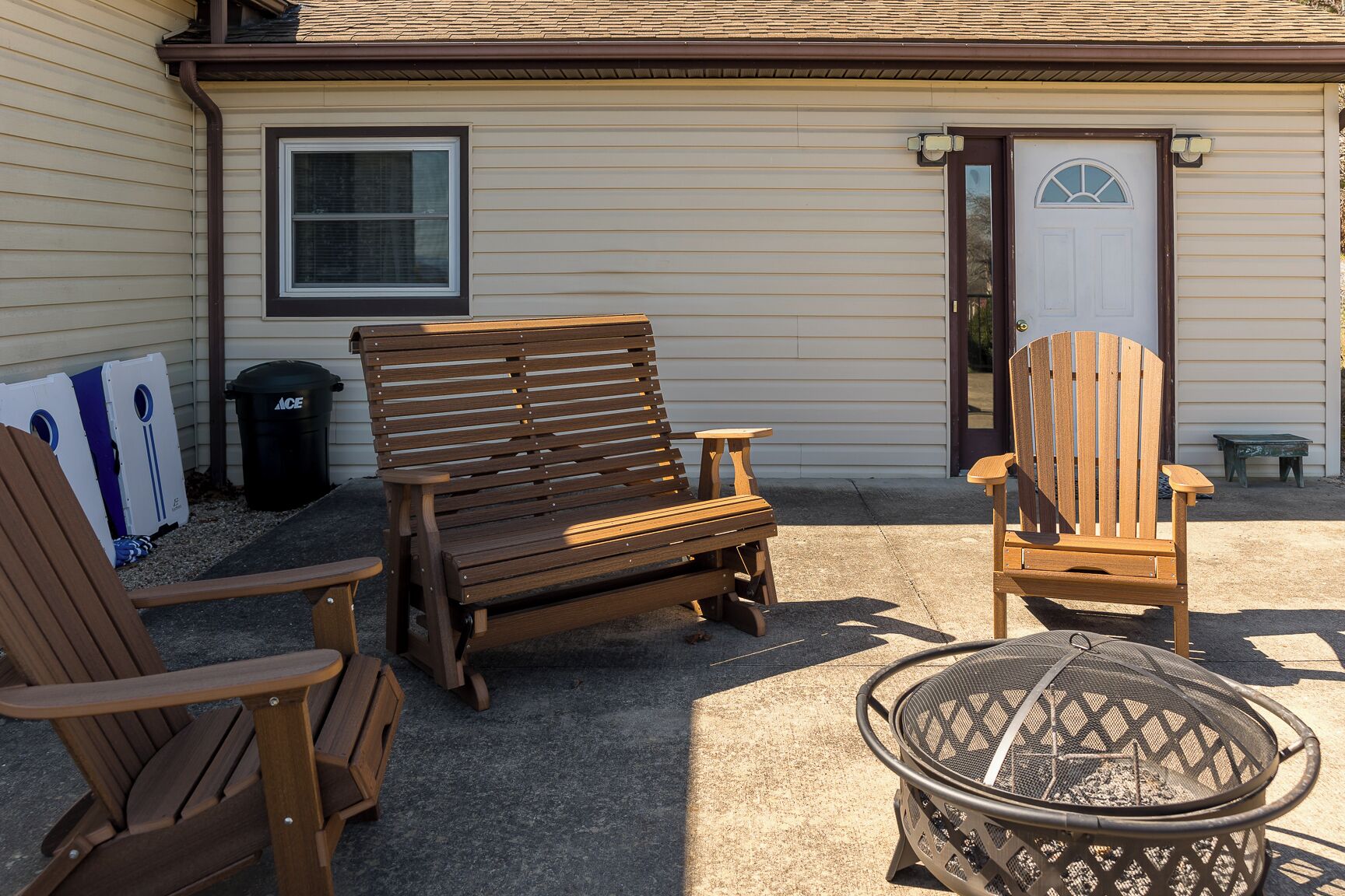 Un'area patio con poltrone in legno tipo Adirondack, un tavolino e un braciere in metallo.
