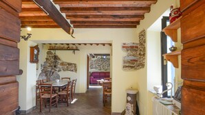 A rustic dining area with wooden furniture, a stone wall, and a vintage stove.