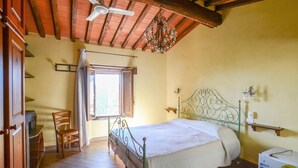 A bedroom with a bed, a chair, a window, and a ceiling fan.