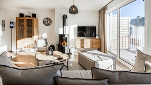 Uma sala de estar moderna com sofá, mesa de centro, lareira, TV e varanda com vista.