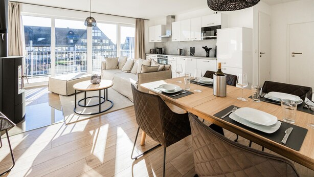 Um apartamento moderno com sala de jantar, cozinha e varanda com vista para edifícios.