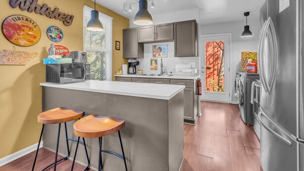 Een moderne keuken met een centraal eiland, barstoelen en diverse keukenapparaten.
