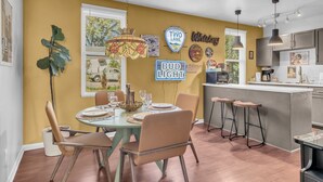 Een eetgedeelte met een ronde tafel voor vier personen, barstoelen en een keuken met een bargedeelte.