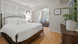 A bedroom with a large bed, a wooden dresser, and a potted plant. - 2BR Downtown Sac - In unit Laundry - Free Parking (Sacramento)