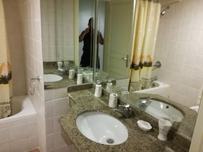 A bathroom with two sinks, a bathtub, and a shower.