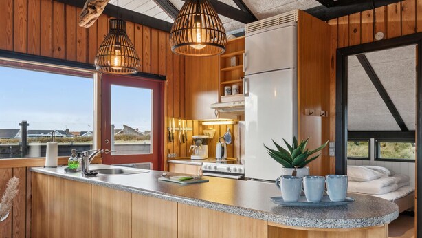 Una cocina moderna con detalles de madera, una isla central y vista al mar.