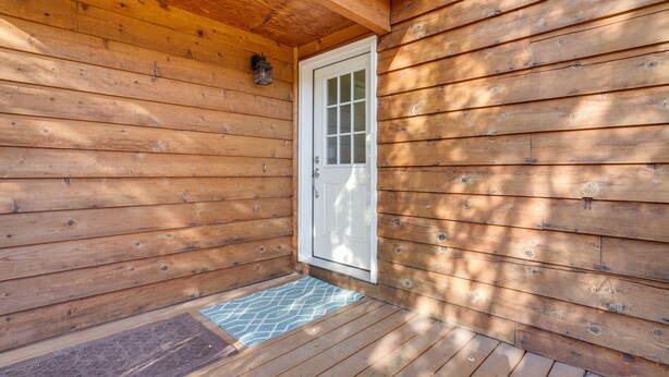 En stuga av trä med en vit dörr och en liten veranda.