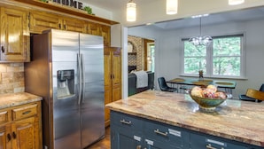 Una cocina moderna con armarios de madera, un refrigerador de acero inoxidable y una encimera de granito.